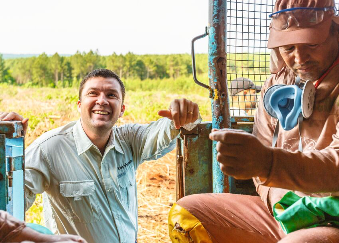 Man standing outside machine smiling and machine operator sitting in machine 