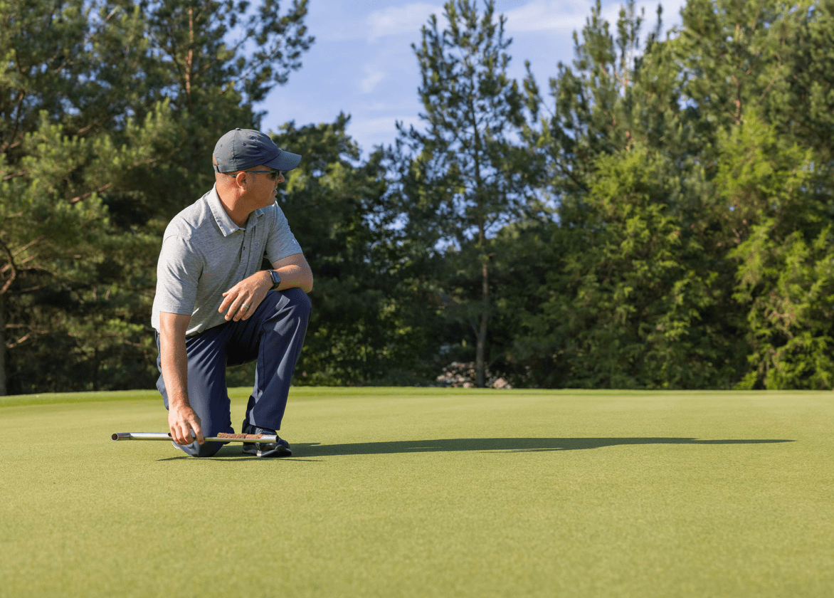 Man examining golf course green