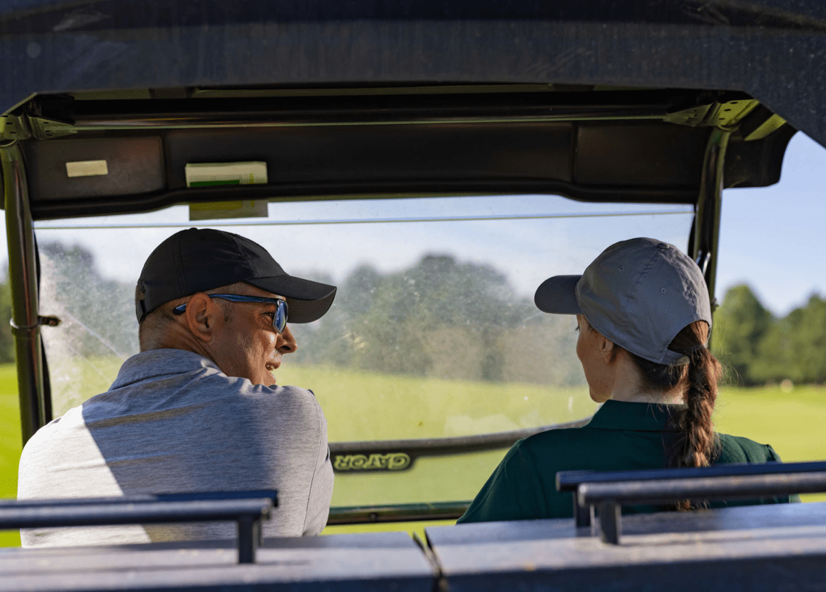 Man and woman sitting in golf cart talking