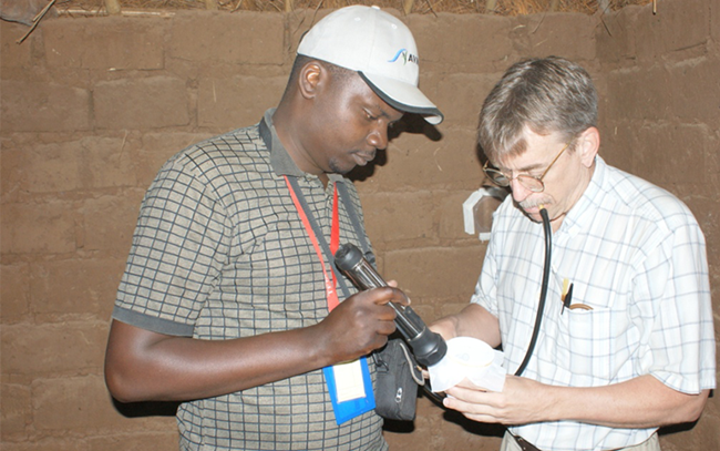 Dr Bangs (right) conducting a wall bioassay to test the efficacy and residual activity of an indoor residual spray used for malaria control.
