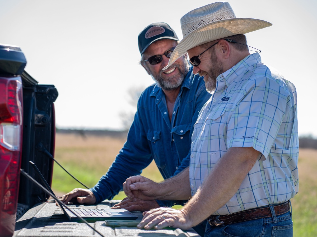 two men standing by truck tailgate viewing laptop
