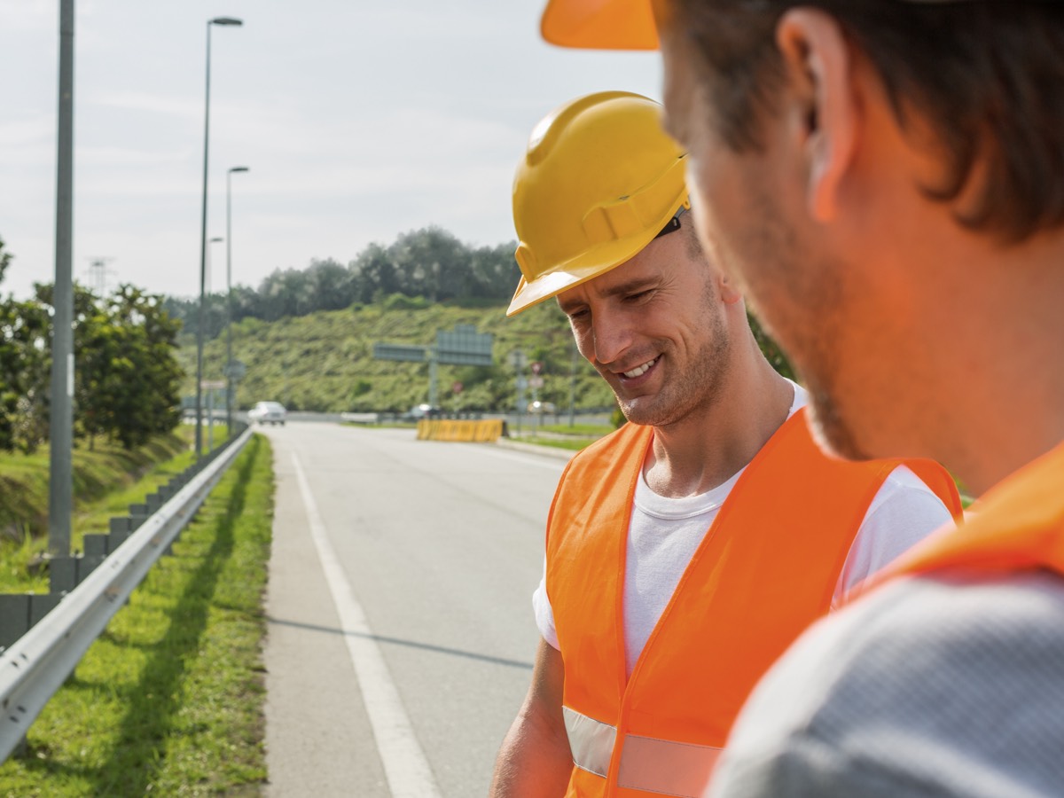 man smiling in safety gear on roadside