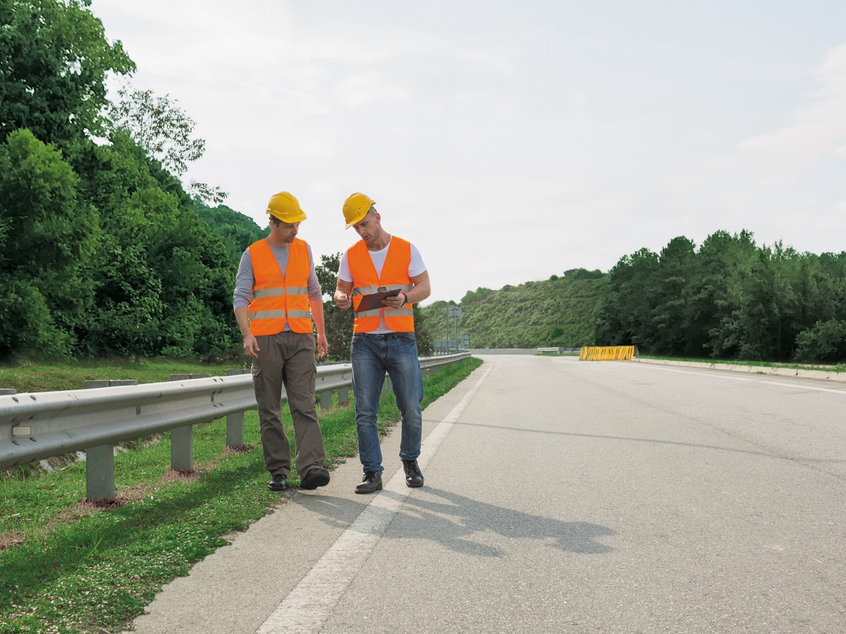 two men in safety gear on a roadside